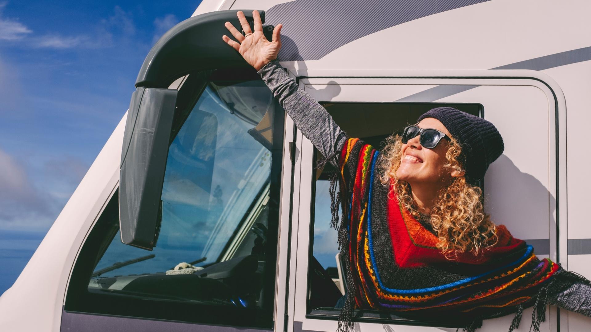 Femme heureuse souriant par la fenêtre d'un camping-car.