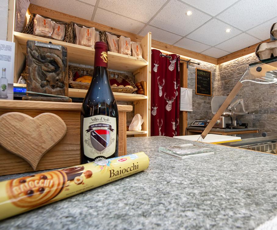 Épicerie avec du vin, des biscuits et des produits frais exposés sur des étagères en bois.
