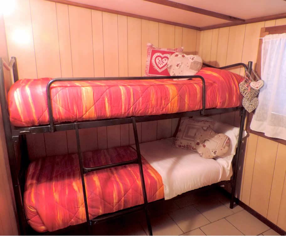 Lits superposés avec des couvertures rouges dans une chambre aux murs en bois.