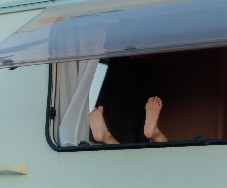 Des pieds sortant par la fenêtre d'une caravane.
